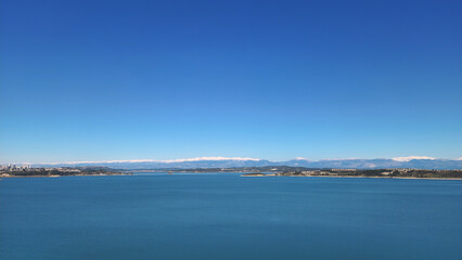 On a winter day, Seyhan Lake extends towards the Bolkar Mountains, with its unique turquoise colors and the majestic snowy peaks of the Central Taurus Mountains in the background.