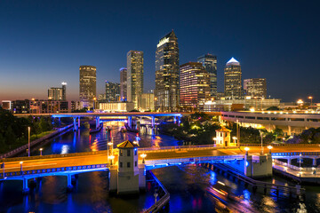 Tampa city in Florida with brightly illuminated highway traffic on bridge and skyscraper buildings...