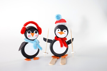 Penguin crafts made from bottle caps, dressed in festive accessories like earmuffs and Santa hats. Ideal for businesses focusing on holiday crafts, upcycling materials, and winter-themed DIY projects.