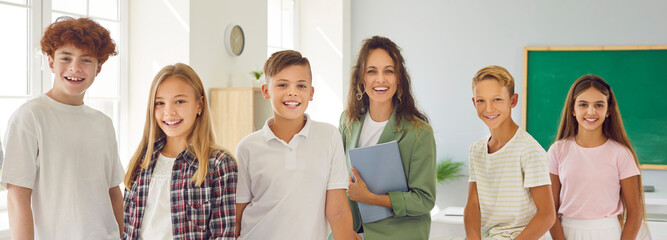 Obraz premium Posing and smiling school children and teacher group photo in classroom funny school days. Smiles of school children shine through capturing essence of carefree childhood Pupils smiling together