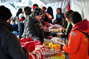 Crowds gather at a winter market where vendors offer handmade goods and local delicacies, creating a lively and warm atmosphere despite the cold weather. Generative AI
