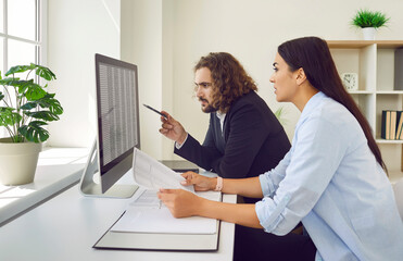 Male and female accountants working with business spreadsheets. Serious young man and woman sitting...