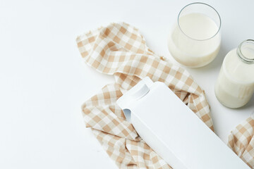Milk Container and Glass of Milk on Checkered Cloth With Additional Bottle in Bright Kitchen Setting