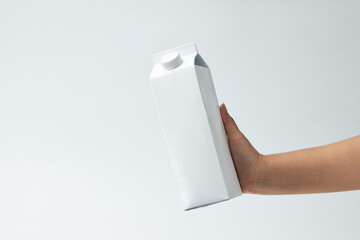 Hand Holding a Plain Milk Carton Against a Light Background Showing Texture and Shape in a Minimalistic Style