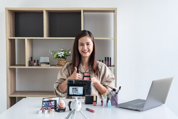 Happy smiling elegant woman or beauty blogger with brush on recording video while review product...