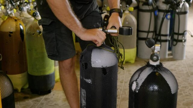 Diving equipment maintenance: Close-up of a diver handling a scuba tank, showcasing preparation and care of gear at a dive center
