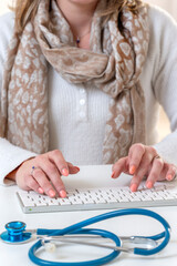 Healthcare worker typing with stethoscope