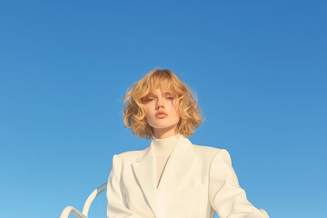 Skyward Stare: A confident woman in an elegant white suit gazes upward, her gaze mirroring the boundless blue of the sky. The image evokes themes of aspiration and modern minimalism.