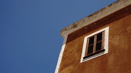 low angle window with shutters against the sky