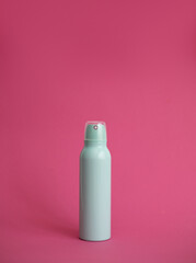 Mint-colored deodorant spray bottle on pink background.