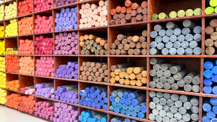 Colorful art pastels neatly arranged in wooden shelves, creative supplies, art workshop, rainbow hues