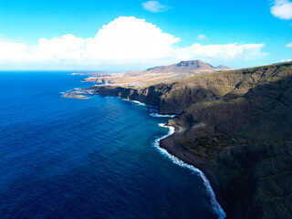 Obraz premium Aerial View of a Rugged Coastal Mountain Range with Dramatic Cliffs and Ocean Waves