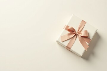 Fototapeta premium A delicately wrapped present, a pristine white box adorned with a blush-toned satin ribbon tied in a perfect bow, sits against a soft off-white backdrop.