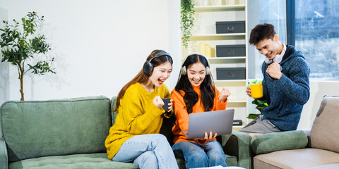 Three Asian young adult students sit in university living room, discussing their study abroad experiences, academic research, preparing thesis report, planning future global education opportunities.