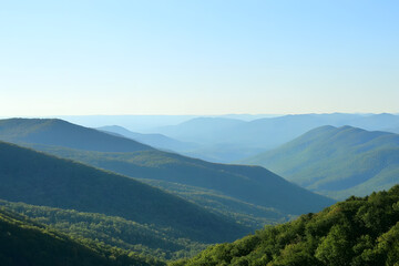 Naklejka premium A breathtaking view of rolling mountains covered in lush greenery, with misty layers creating a serene and tranquil atmosphere, perfect for nature and travel enthusiasts.