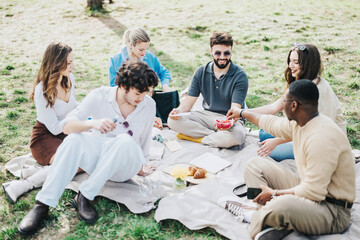 A cheerful group of friends gather on a sunny day, sharing food and laughter during a relaxing picnic in the park. The image captures the essence of friendship and outdoor leisure.