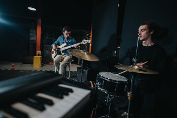 A musical ensemble performing live in a dimly lit studio, featuring a bassist and a drummer. Capturing a lively environment of music, creativity, and teamwork.