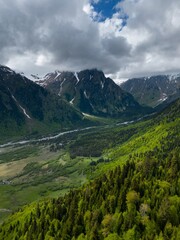 Obraz premium valley meadows mountains, steep peaks in clouds, flight over forest, aerial view