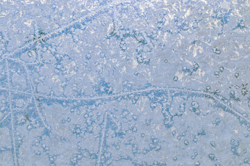 Close-up of frost patterns on a window with colorful background