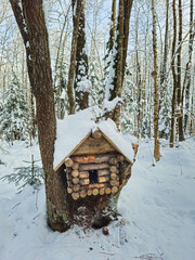 A wooden birdhouse shaped like a log cabin. Wintertime.