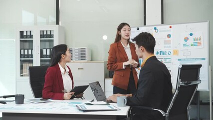 Three Asian business professionals gather in boardroom for annual meeting, discussing strategic goals, future projections while proposing ideas, engaging in decision-making for corporate growth.