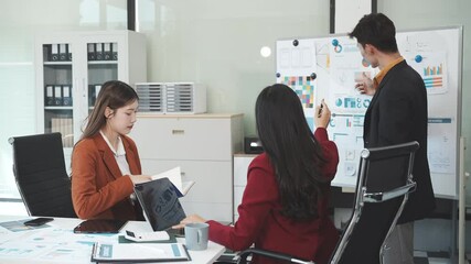 Three Asian business professionals gather in boardroom for annual meeting, discussing strategic goals, future projections while proposing ideas, engaging in decision-making for corporate growth.