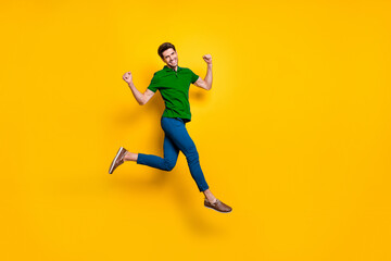 Fototapeta na wymiar Full length body size photo of cheerful positive strong man running jumping demonstrating his powerful muscles wearing blue pants trousers purple t-shirt isolated over vivid color background