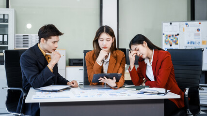 Three Asian business professionals gather in boardroom for annual meeting, discussing strategic goals, future projections while proposing ideas, engaging in decision-making for corporate growth.