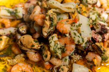 A delicious seafood dish featuring shrimp, scallops, and mussels is served on a plate. The shrimp...