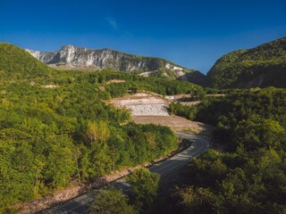 Aerial view flying above serpentine road, against backdrop mountain peaks sunset
