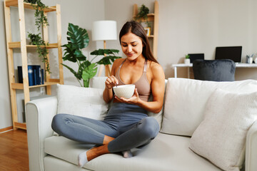Fit woman enjoying a healthy breakfast in her modern apartment, promoting a balanced lifestyle
