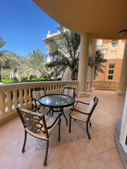 Elegant outdoor seating area in a luxury villa surrounded by palm trees on a sunny day