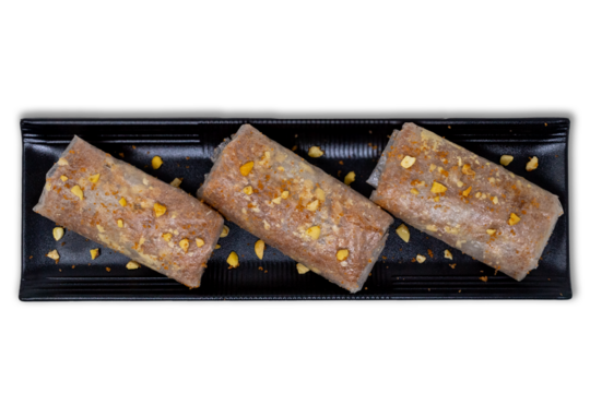 Putharekulu pootarekulu Pootharekulu - tradional South Authentic Andhra Sweet with Crispy Rice Paper, Jaggery, and Nuts on a Black Plate with transparent background PNG