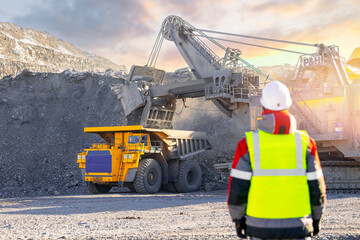 Winter coal mining operation with machinery and worker in high visibility clothing