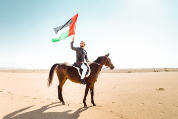 Young adult with Kandura, the emirates traditional clothes, riding his horse in the desert