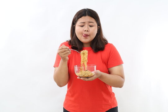 Ecstatic and salivate Asian woman holding a bowl of fried instant noodles.