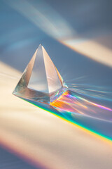 Minimalist macro shot of a triangular glass prism refracting light into a rainbow
