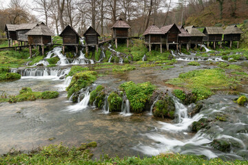 Small wooden water mills on poles on Pliva river near Jajce during overcast day