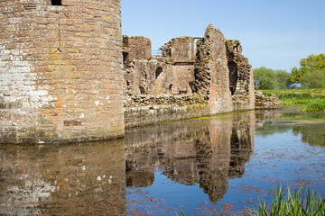 Castle ruins reflection in the surrounding moat on a clear sunny day in Southern Scotland.