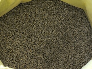 bag surrounded by pressed pellets of farm poultry feed, top view, example of factory-produced combined balanced feed for farm poultry