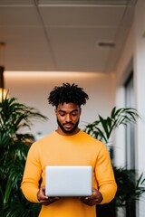 Focused individual in bright orange sweater engaging with laptop