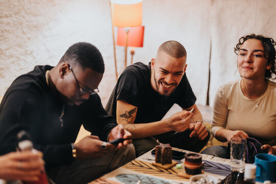 A group of young diverse friends socializing and enjoying each other's company in a comfortable indoor environment, showcasing friendship, relaxation, and connection.