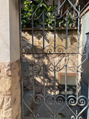 Wrought iron gate casting shadows on stone wall, elegant garden entrance, architectural detail,...
