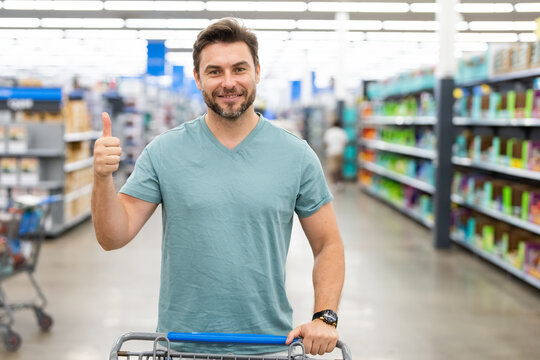 Man with grocery shopping trolley shopping at supermarket. Grocery store, shopping basket. Banner with man for grocery food store or supermarket. Man choosing food in store or grocery store.