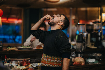 A man in a warmly lit lounge bar savors his food while enjoying the relaxed atmosphere. The bar's ambience is inviting, featuring cozy lighting and vibrant decorations to create a joyful setting.