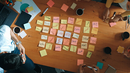 Top down view of smart diverse business people writing marketing idea at meeting and brainstorming...