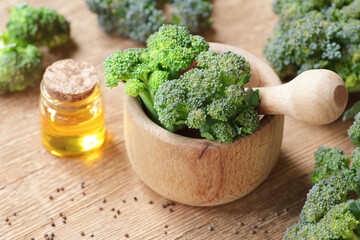Fresh brocoli in a wooden bowl on the kitchen table with oil and seeds close, greeb vegetavle, source of sulforaphane, healrhy food diet concept