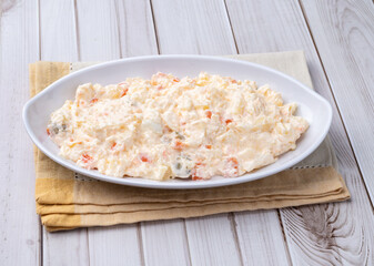 Russian salad or mayonnaise salad in a plate over wooden table