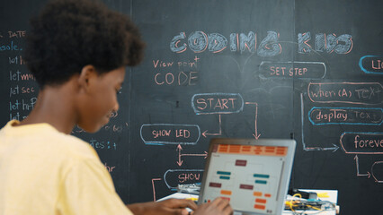 African boy using laptop programing system or coding prompt at blackboard with science theory....