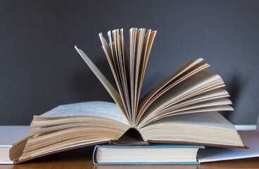 Fototapeta premium Pile of books on wooden table with dark background and copy space.